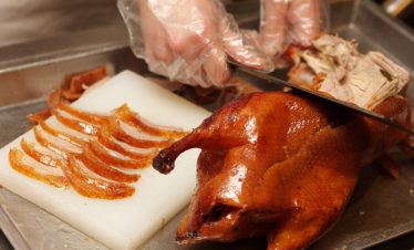 Chinese cook prepares Peking Roast Duck. Peking Duck is a famous duck dish from Beijing that has been prepared since the imperial era, and is now considered one of China's national foods.