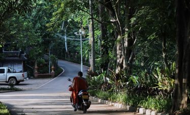 Local resident riding motorbike on country road in Manyuan Village Xishuangbanna Yunnan