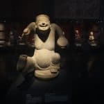 A lifelike statue from Sanxingdui, Sichuan, China, depicting a joyful figure.