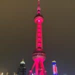 The Shanghai TV Tower illuminated in red lights, creating a dramatic effect over the skyline.
