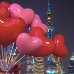 The scenic Bund in Shanghai, China, with the Oriental Pearl Tower behind red heart-shaped balloons.