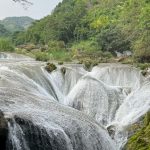 The stunning Huangguoshu Waterfall in Guangxi, China, with cascading waters and rocky terrain.
