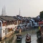 Traditional boats sailing through the shimmering waters of ZhuJiaJiao Water Town,Shanghai China.