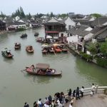 Boats gliding across the water in ZhuJiaJiao Water Town, China, with spectators observing.
