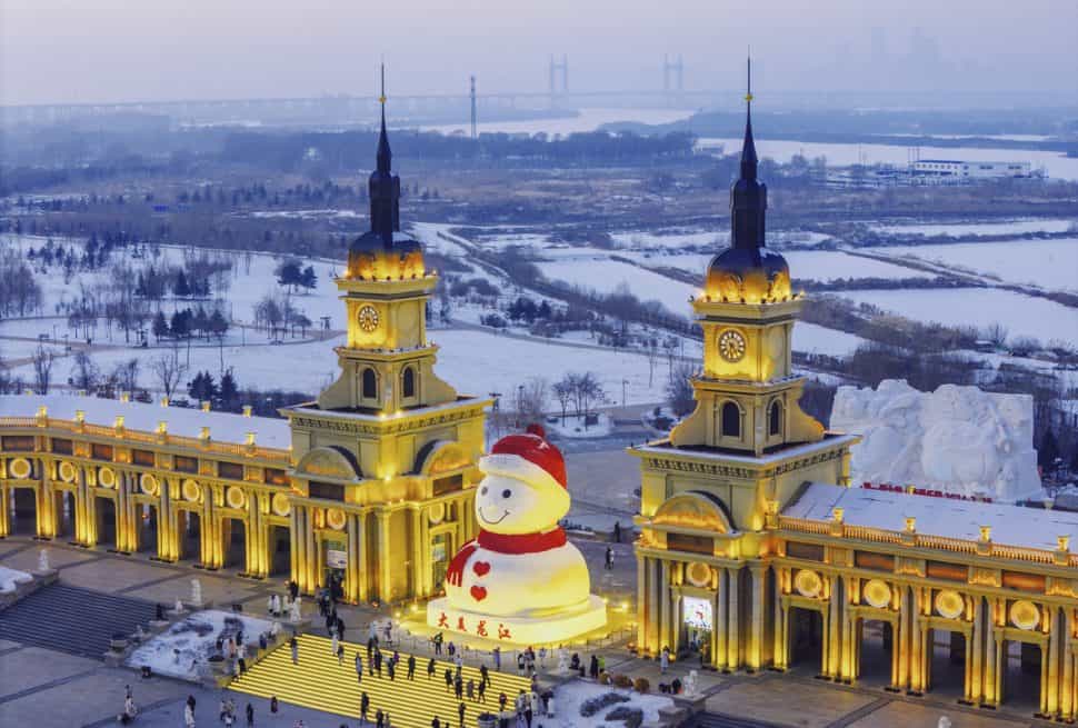 Night view of Harbin Ice and Snow Festival in China with giant snowman and Russian-style buildings