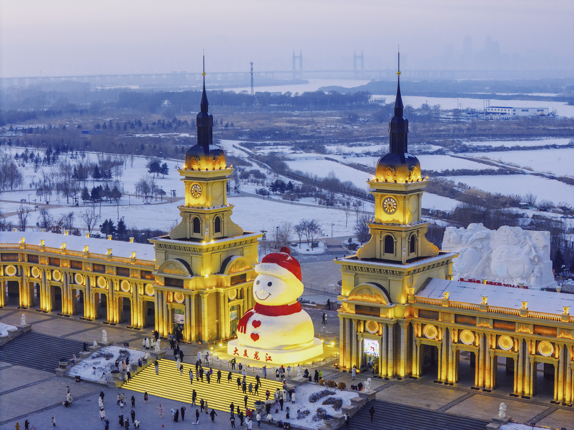 Night view of Harbin Ice and Snow Festival in China with giant snowman and Russian-style buildings